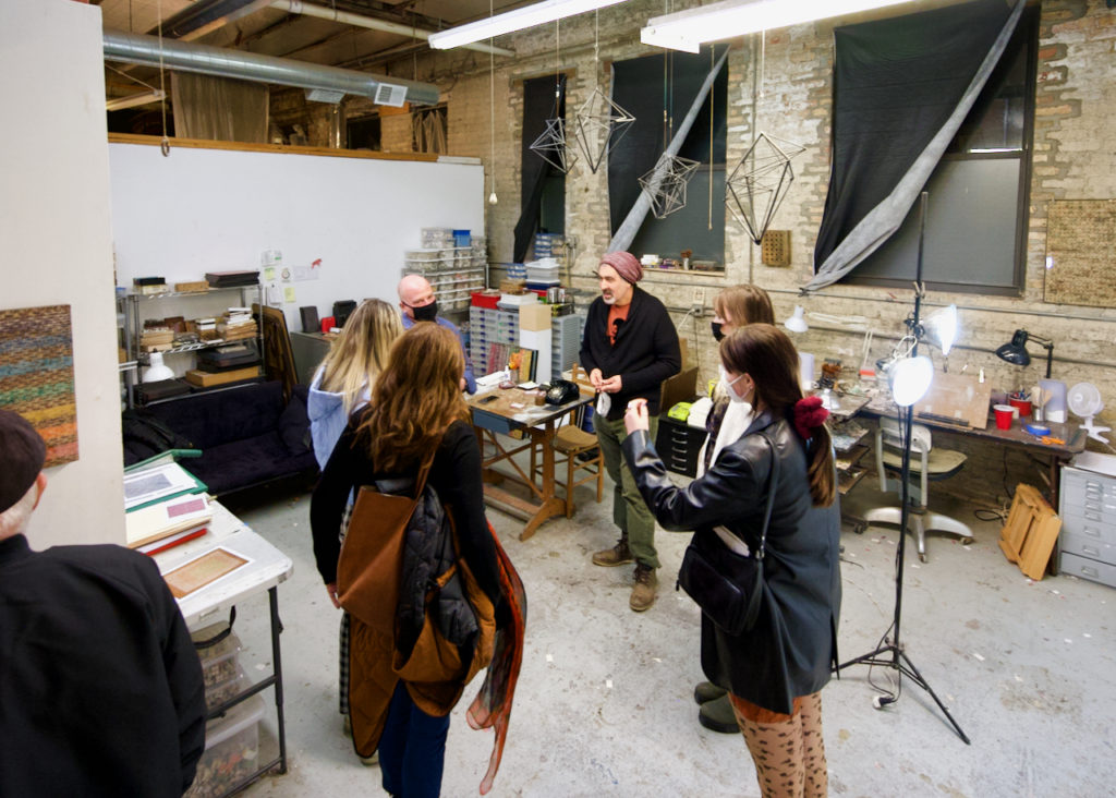 Group of guests standing in a studio with work materials and equipment