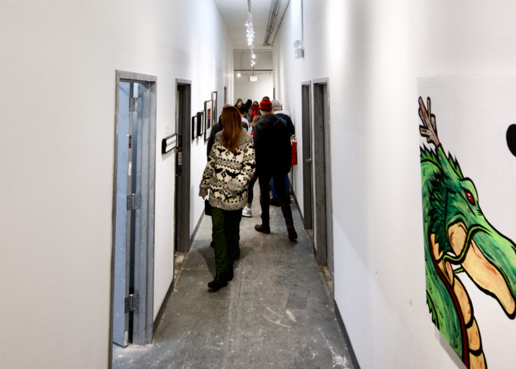 Long hallway with exhibition goers and art hanging on walls