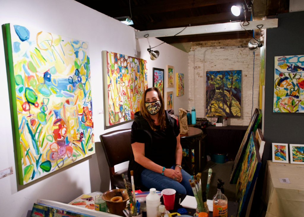 Woman sitting in her studio with artwork displayed