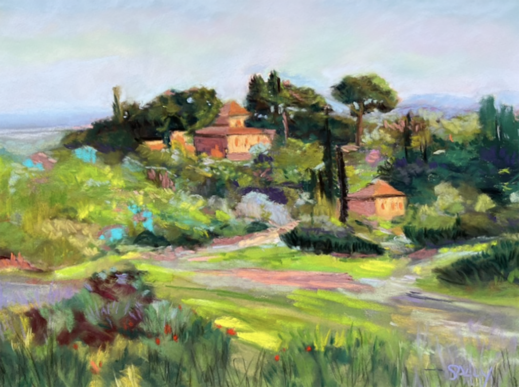 A scene of a some houses in the Italian countryside. Two small tan-colored houses with red terra cotta roofs are seen among some trees and green hills and face a late-afternoon sun. Some taller hills are faintly visible in the distance behind the little estate.